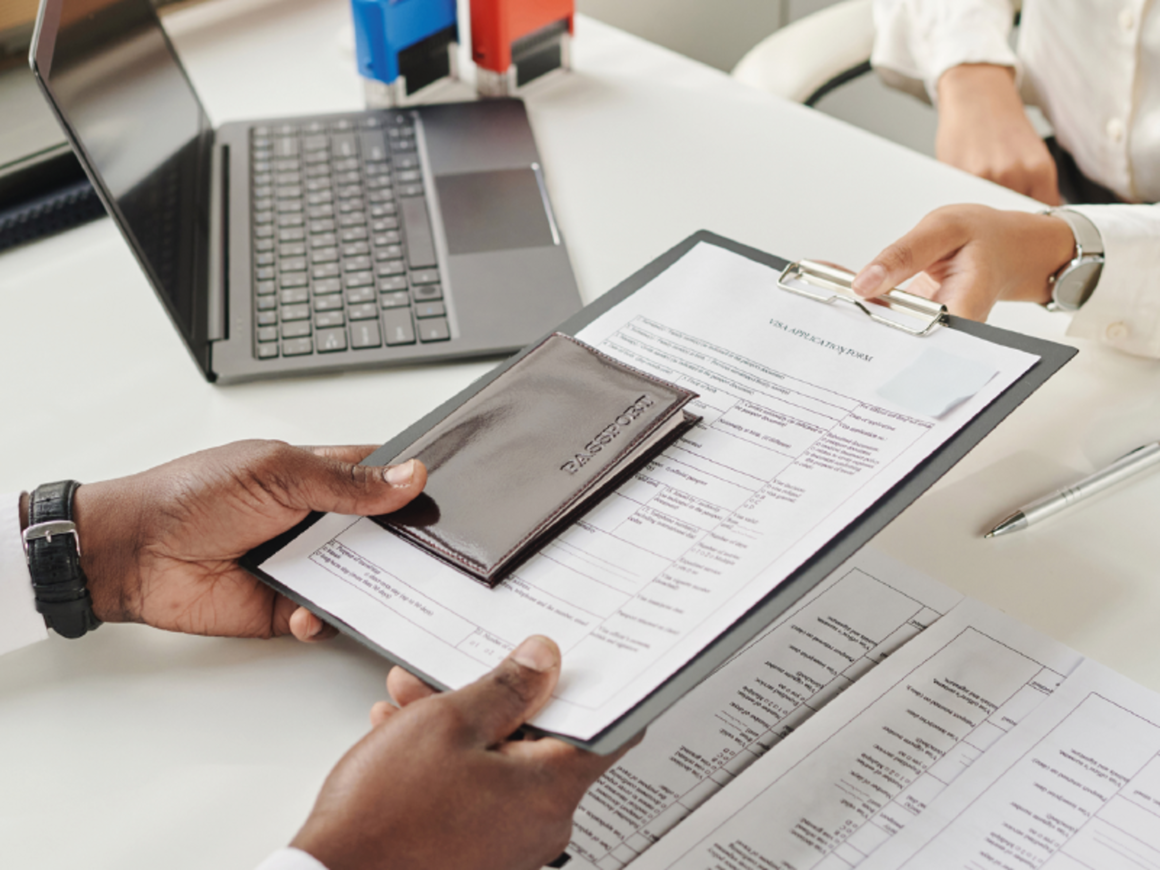 someone hands over a passport and visa documents to an individual sitting across
