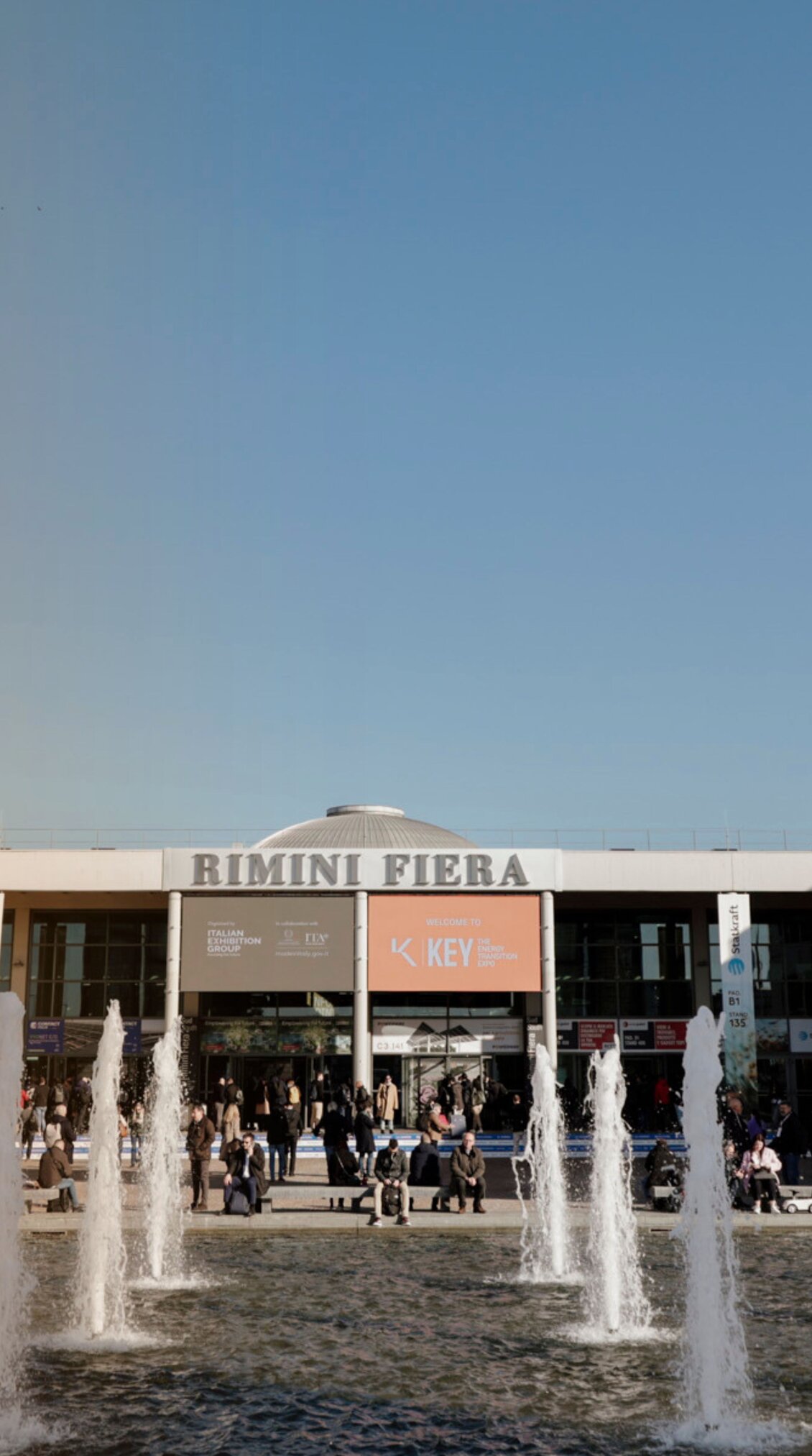 South entrance of the Rimini Expo Centre during K.E.Y., with fountains in the foreground and many visitors in front of the entrance South entrance of the Rimini Expo Centre during K.E.Y., with fountains in the foreground and many visitors in front of the entrance